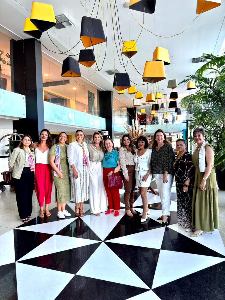 Delegation gathered in a hotel lobby beneath a cluster of yellow and black pendant lampshades.