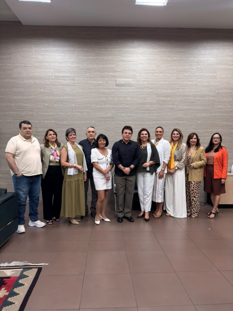 Group portrait of eleven delegates and local hosts against a wood-panelled wall in a meeting room.