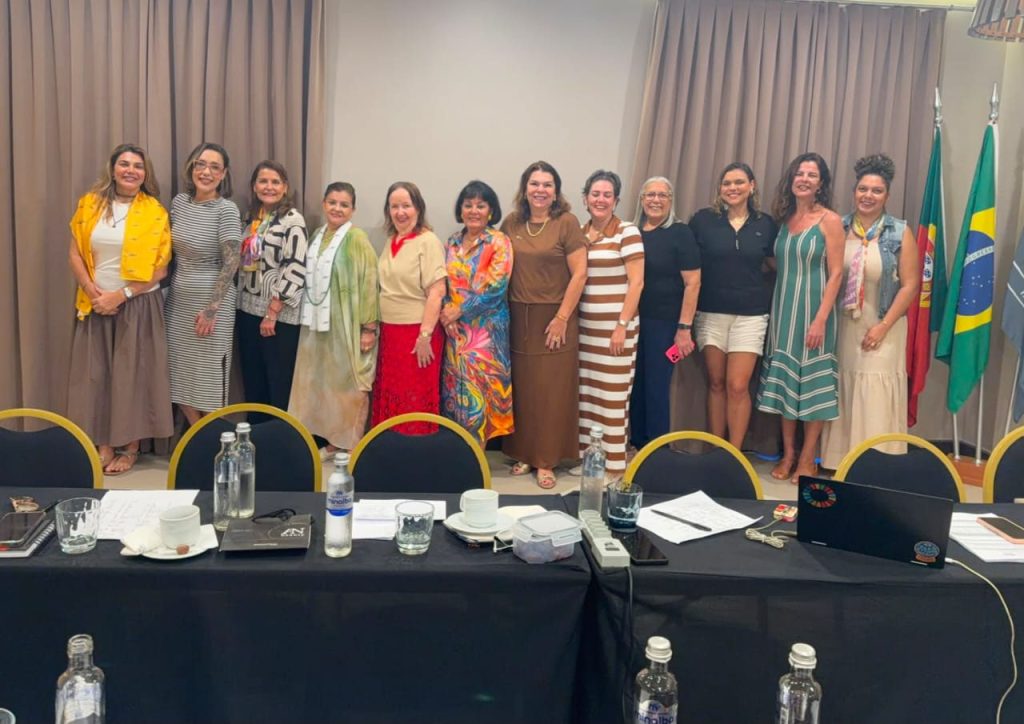 Twelve participants lined up beside Portuguese and Brazilian flags at the end of a planning meeting session.